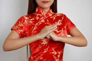 Close up short of young Asian woman hands in red Chinese dress traditional cheongsam qipao with gesture of congratulation with white screen isolated (Chinese new year concept)