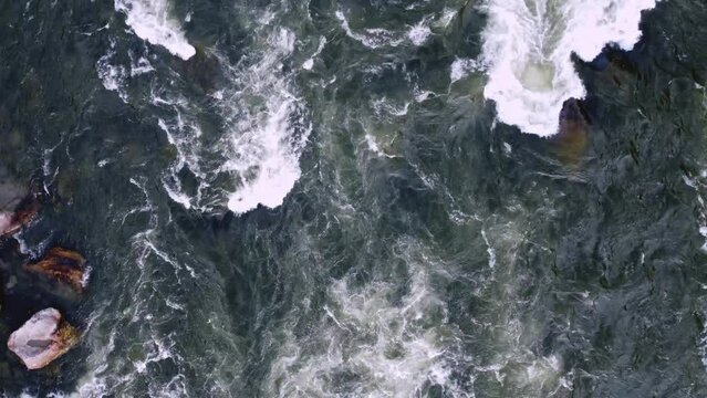 The turbulent flow of a mountain river among the stones. Flying with a top view of a mountain river