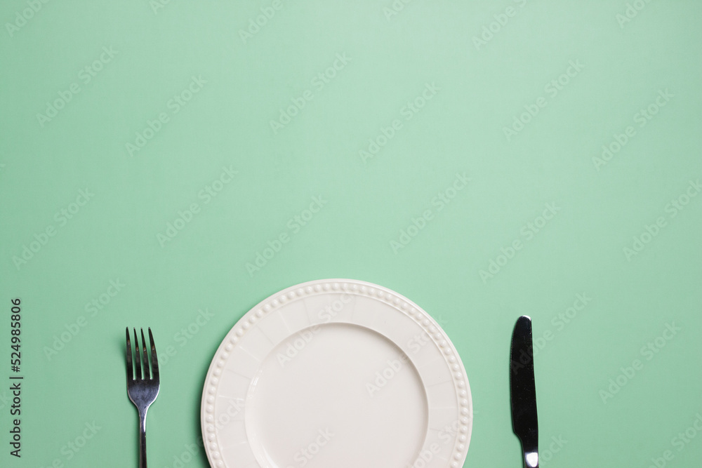 Wall mural an empty plate with knife and fork over the green background.