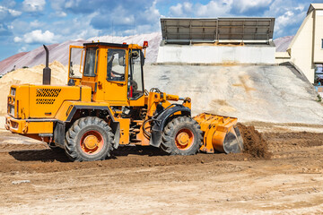 A large front loader pours sand into a pile at a construction site. Transportation of bulk materials. Construction equipment. Bulk cargo transportation. Excavation.