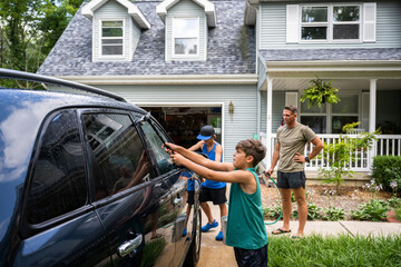Obraz premium Air Force service member washes his vehicles with his sons in the driveway.