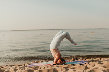 Caucasian woman practicing yoga at seashore sandy beach on sunrise. Womens health and wellness. Sports body positive. Real instructor poses
