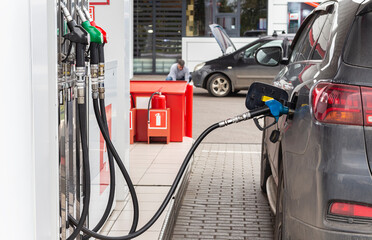 Refueling car with gasoline or diesel fuel at gas station. Black car being fueled by.