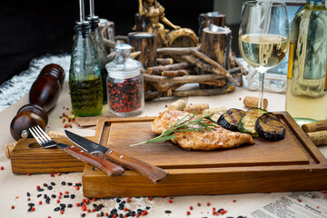 grilled fillet on a wooden board with zucchini and a sprig of rosemary
