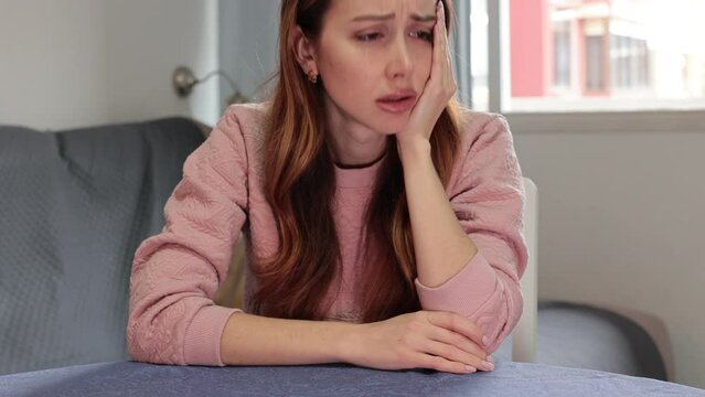 Upset young woman is worried while sitting at the table