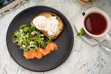 bruschetta with a poached egg in a plate with salmon and fresh herbs
