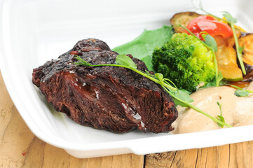 baked meat with broccoli and vegetables in a disposable dish
