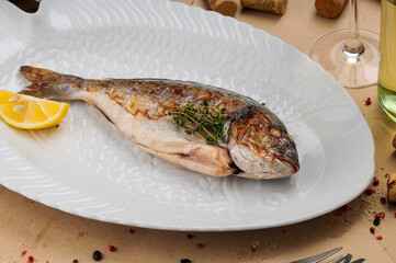 whole fried fish in a white plate with lemon
