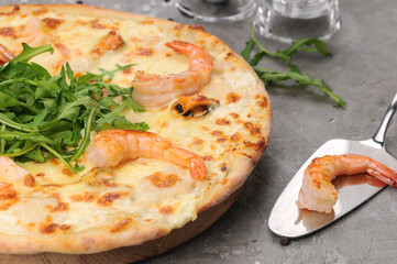 pizza with shrimp and cheese on gray with a spatula
