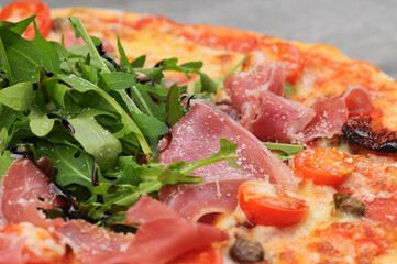 pizza with ham, arugula, tomatoes and cheese macro photo
