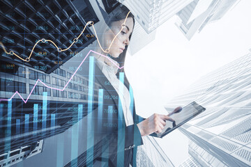 Attractive young european businesswoman using pad with creative growing financial forex chart graph...