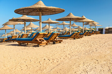 Beach with sunbeds, umbrellas and yellow sand.