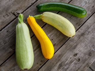 fresh mixed yellow, white, stripped and green zucchini's on a wooden background. Top view flat lay, close up