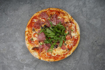 pizza with bacon and arugula on a gray background

