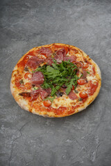 pizza with bacon and arugula on a gray background, vertical photo
