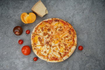 Margherita pizza on a gray background with tomatoes and cheese
