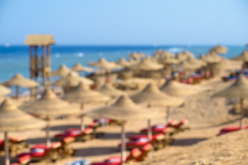 Beach with sunbeds, umbrellas and yellow sand. Defocused background.