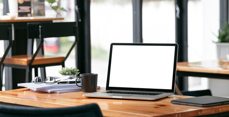 Creative workspace, blank screen laptop computer on wooden table, mockup blank screen laptop.