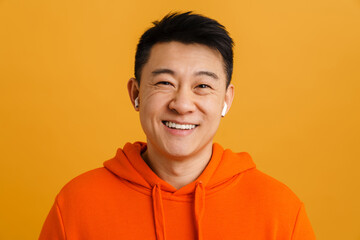 Brunette adult asian man wearing earphones smiling at camera