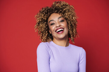 Young black woman with afro curls smiling and posing at camera