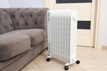 Concept of heating season, modern electric heater near sofa