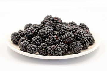 Black mulberry isolated on white background. Fresh and juicy black mulberry on the plate. Organic food. close up