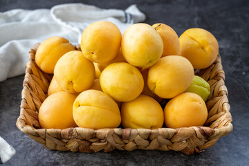 Ripe apricots on a dark background. Fresh and juicy apricots in the basket. Organic food. close up