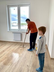 Father and son washing the floor in a new apartment, life style, the concept of moving to a new house, cleaning the apartment