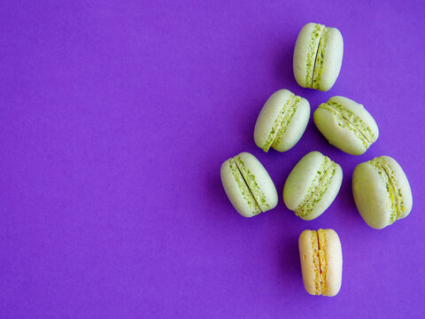 French mint pistachio green tea macarons shaped as Christmas tree on purple background. Top view flat lay, copy spase