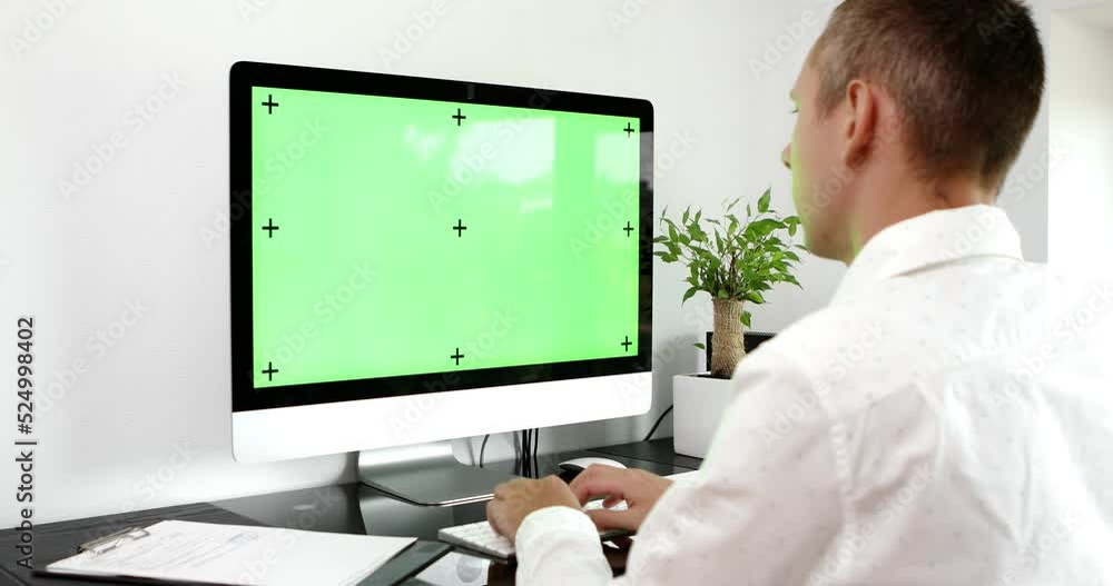 Poster green screen. employee working at computer sitting at desk. view from back.
