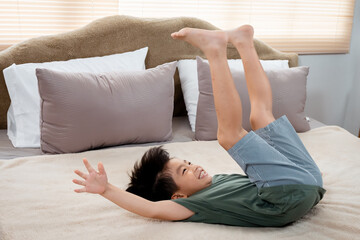 Asian boy, handsome, The boy was wearing a green t-shirt, .jumping on the bed and went down to lie down and turn around, until he was sweating, without feeling tired, he looks happy.