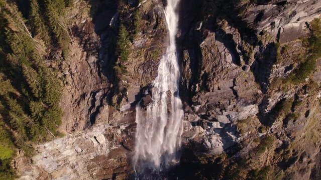 aerial drone footage orbiting counterclockwise around a breathtaking waterfall in springtime in Grindewald in Switzerland