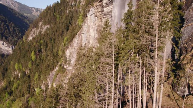 aerial drone footage raising up revealing picturesque dreamy waterfall in Grindelwald in the Swiss Alps