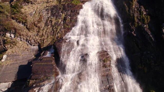aerial drone footage raising down a picturesque waterfall in springtime with colorful light reflections at Fallbach in Grindelwald in Switzerland