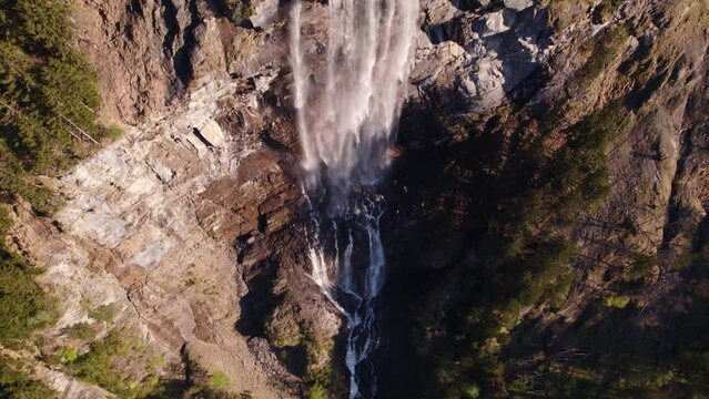 aerial drone footage raising up with top down views of a picturesque waterfall in Grindelwald, Switzerland
