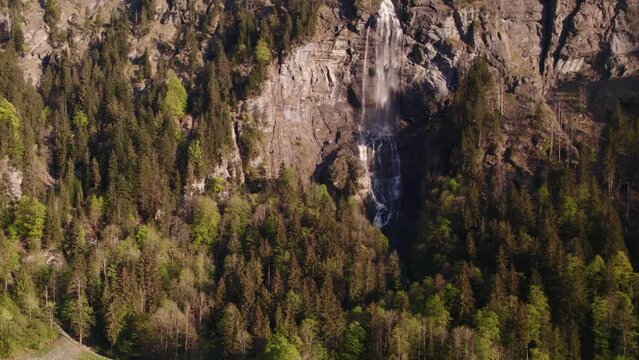 aerial drone footage raising up from a distance with stunning views of Fallbach, a stunning waterfall in Grindelwald, Switzerland