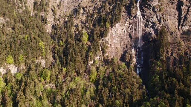 aerial drone footage pushing in from a distance with dreamy views of Fallbach, a stunning waterfall in Grindelwald, Switzerland
