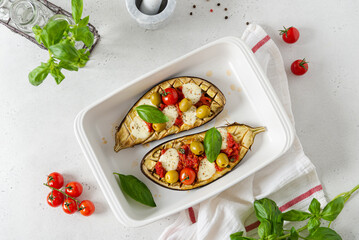Delicious baked eggplants. Aubergines stuffed with vegetables, olives and cheese in a baking dish. Top view. Vegetarian food. Seasonal recipe.