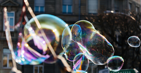Multiple balloon bubble made from soap - flying above the city with apartment building in...