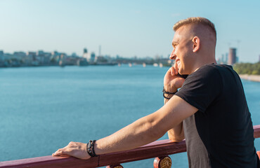 Young man talking over phone on a bright sunny day, guy using mobile phone outdoor. Portrait of a man in a conversation through mobile phone.