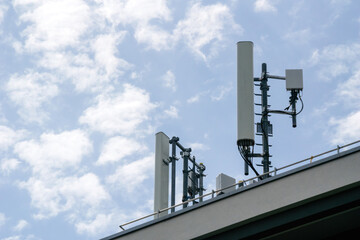 Multiple antenna on the rooftop of a house with scattered clouds in background 5G 4G LTE