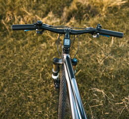 Fototapeta na wymiar Bike handlebars. First-person view of mountain bicycle on the forest path. Riding a bike in a beautiful summer sunset nature landscape.