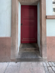 Fototapeta na wymiar View from the street at welcoming cleanly painted red door with black steel door handle