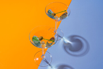 Two classic dry martini with olives on color background.