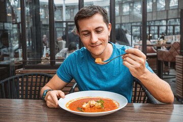 Man eating delicious tomato soup in cafe or restaurant. Vegetarian cuisine and healthy vegetable...