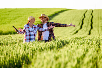 Man and woman are working together. They are cultivating wheat. They are happy because of good...