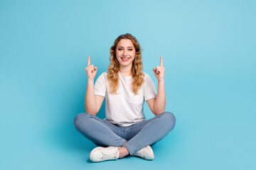 Fototapeta na wymiar Photo of charming young woman dressed shirt smiling pointing finger up empty space isolated blue color background