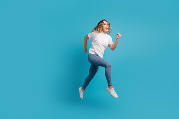 Fototapeta na wymiar Full size profile side photo of young beautiful happy positive smiling girl running isolated on blue color background