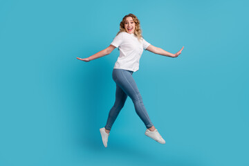 Fototapeta na wymiar Full size profile side photo of young beautiful happy smiling girl running isolated on blue color background