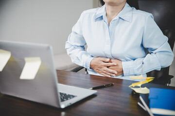 Young asian business woman person sitting at work and has stress pain in her stomach. Concept...